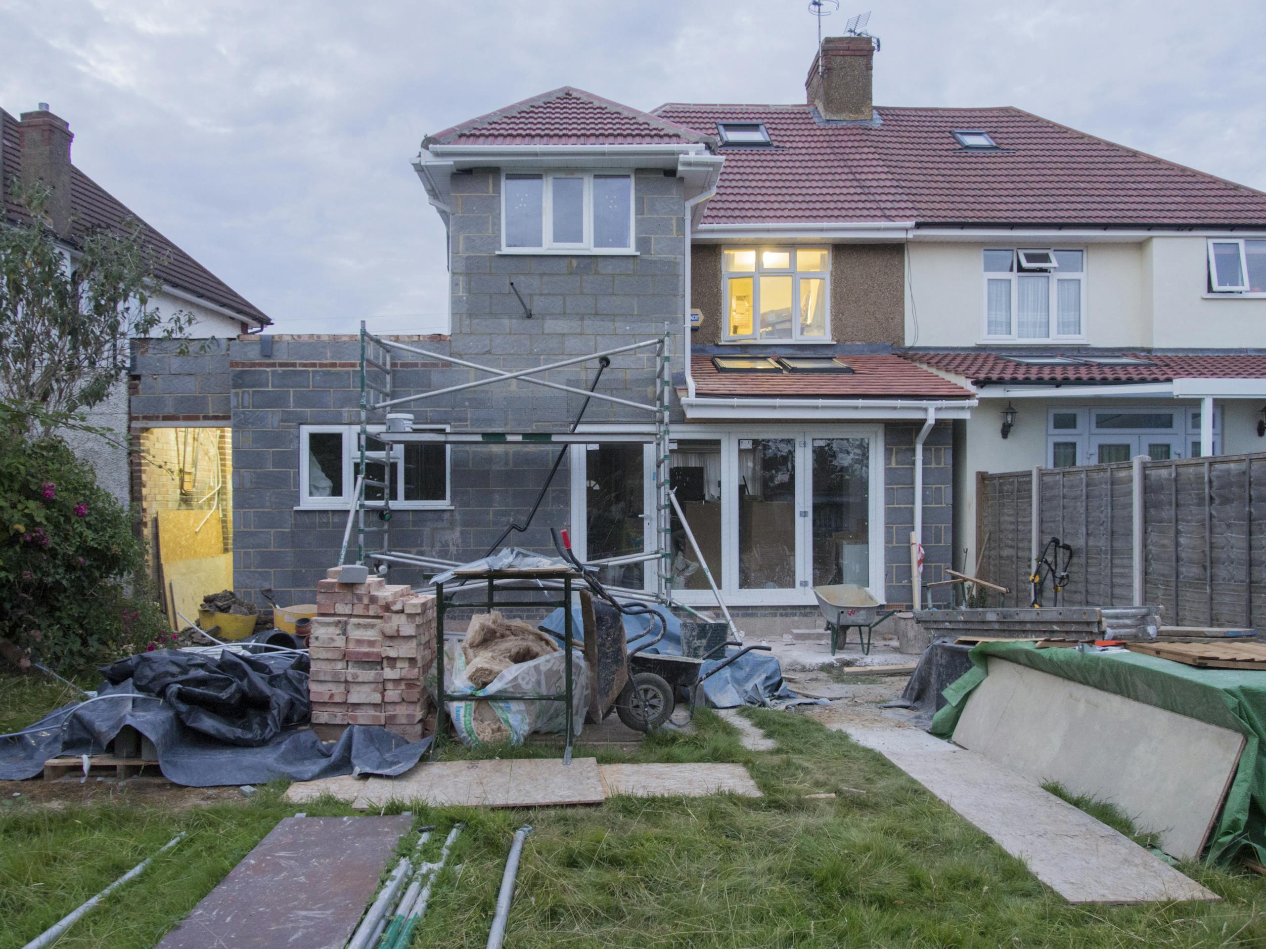 A suburban house undergoing major renovations with scaffolding and building materials.