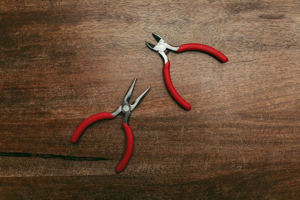 Close-up of two red-handled pliers on a wooden surface, perfect for tool-related themes.