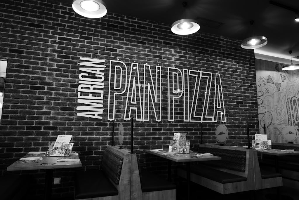 Black and white image of an American pan pizza restaurant with stylish brick wall decor.